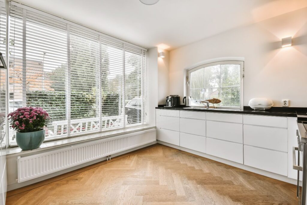 Bright renovated kitchen with white cabinetry under a large window